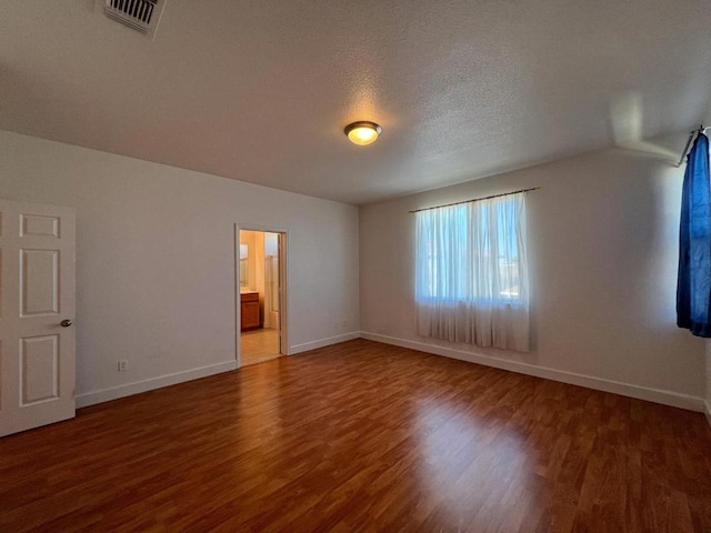 interior space with dark wood-type flooring, a textured ceiling, and ensuite bath