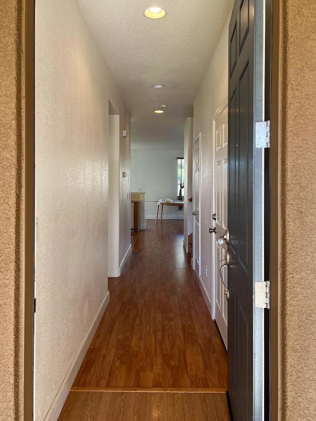 hallway featuring dark hardwood / wood-style floors and a textured ceiling