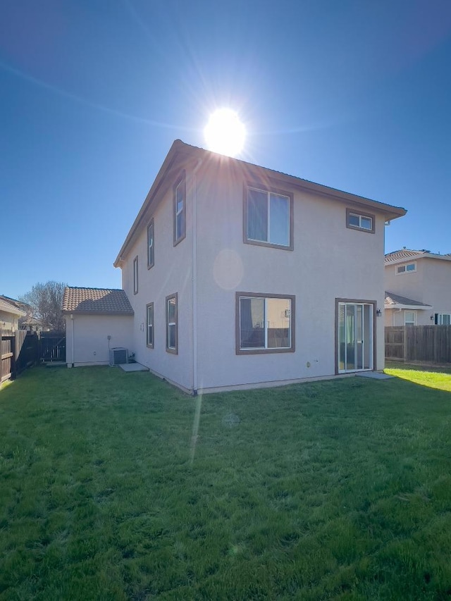 rear view of property featuring cooling unit and a lawn