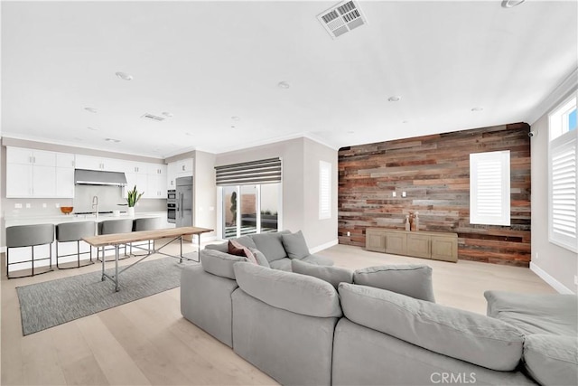 249 Chorus, Irvine, CA 92618 - living room featuring baseboards, visible vents, wood walls, an accent wall, and light wood-style floors