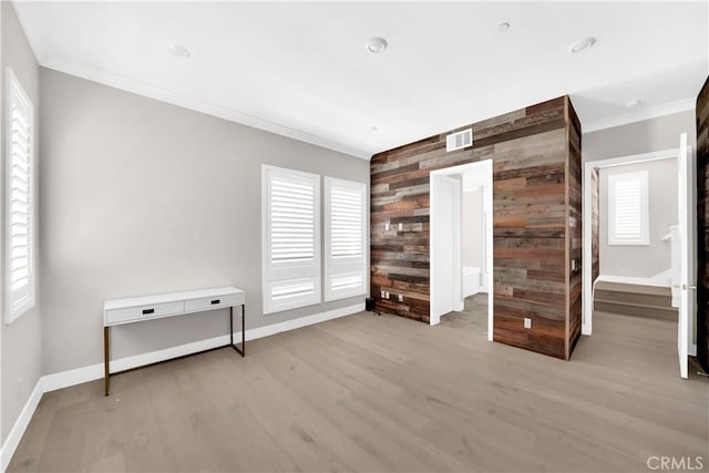 unfurnished bedroom featuring crown molding, light hardwood / wood-style floors, and wood walls