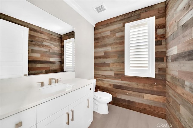 bathroom with vanity, toilet, and wood walls