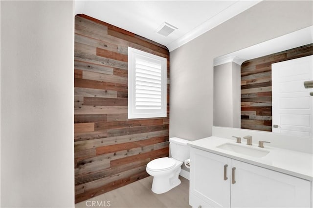 bathroom with vanity, toilet, and wood walls