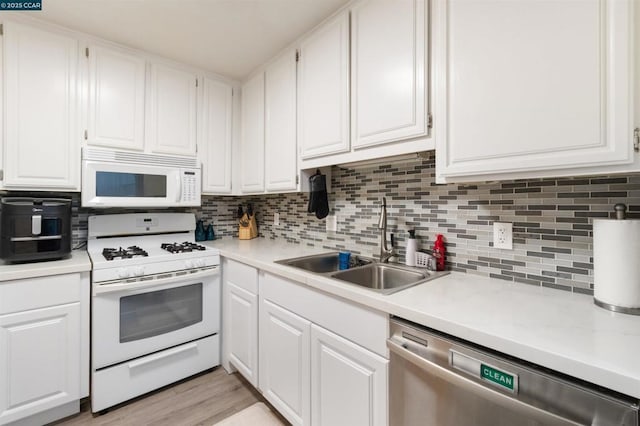 kitchen with white cabinetry, sink, white appliances, and tasteful backsplash