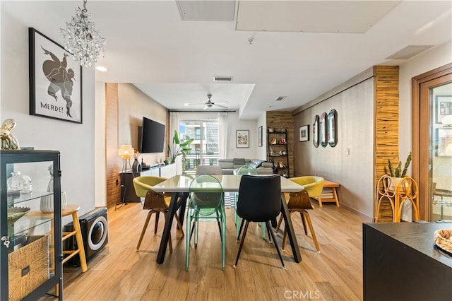 dining space featuring ceiling fan with notable chandelier and light wood-type flooring