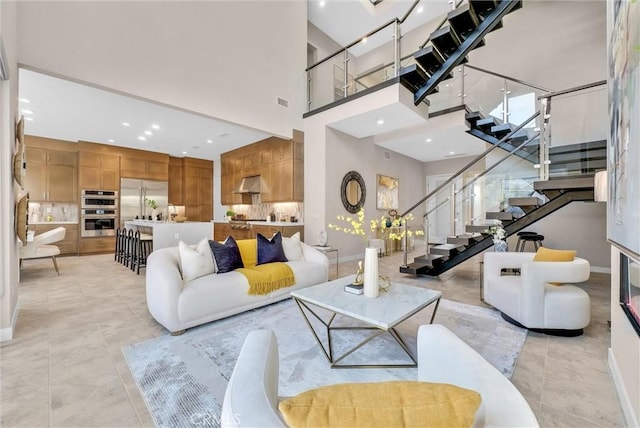 living area with light tile patterned floors, recessed lighting, a towering ceiling, baseboards, and stairs