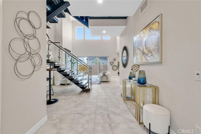 foyer with a wealth of natural light, stairway, a high ceiling, and visible vents