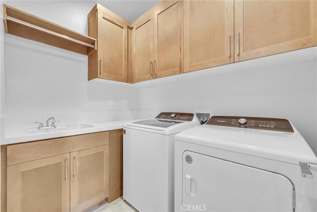 laundry area featuring washing machine and dryer, cabinet space, and a sink