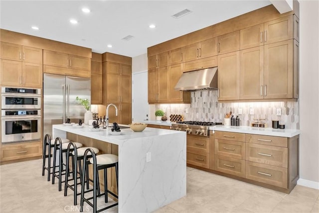 kitchen with a breakfast bar area, visible vents, backsplash, appliances with stainless steel finishes, and under cabinet range hood