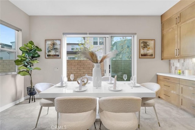 dining space featuring light tile patterned floors, plenty of natural light, and baseboards