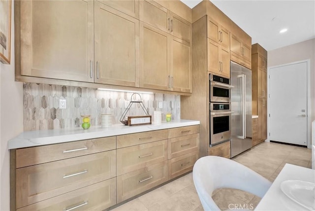 kitchen featuring light countertops, tasteful backsplash, stainless steel double oven, and light brown cabinets