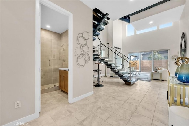 interior space with light tile patterned floors, recessed lighting, a towering ceiling, stairway, and baseboards