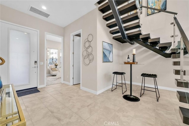 tiled foyer entrance with visible vents, baseboards, and stairs