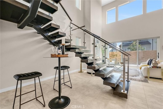 stairway with a high ceiling, baseboards, and tile patterned floors