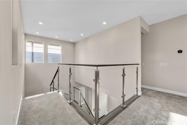 hallway featuring recessed lighting, baseboards, carpet flooring, and an upstairs landing