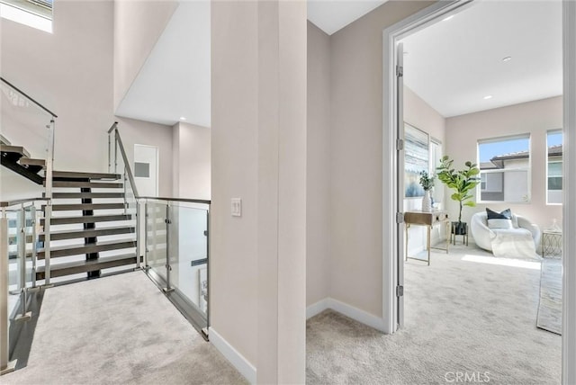 hall featuring carpet floors, baseboards, and stairs