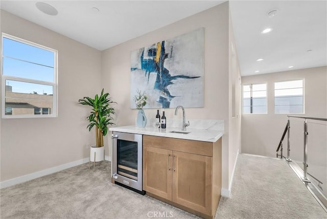 bar with beverage cooler, light carpet, a sink, and baseboards