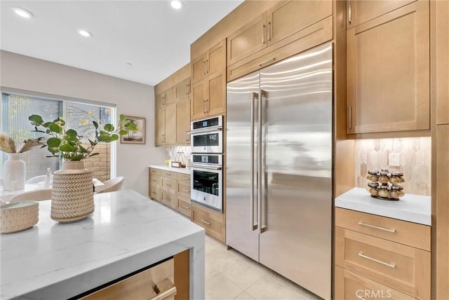 kitchen featuring light tile patterned floors, appliances with stainless steel finishes, light stone counters, backsplash, and recessed lighting