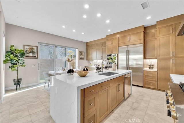 kitchen with light tile patterned floors, an island with sink, stainless steel appliances, a sink, and recessed lighting