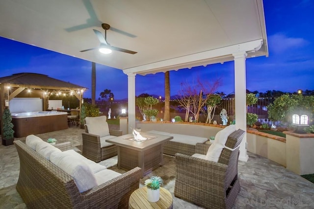 patio terrace at dusk featuring a gazebo, an outdoor living space with a fire pit, and ceiling fan