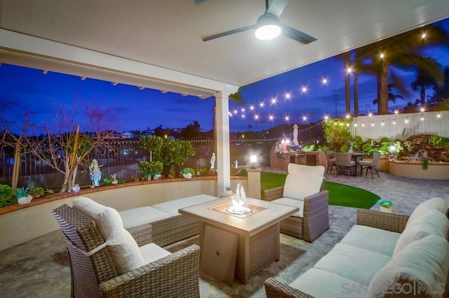 view of patio / terrace featuring ceiling fan and an outdoor living space with a fire pit