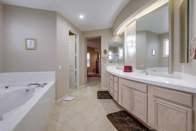 bathroom with tiled tub, vanity, and tile patterned flooring