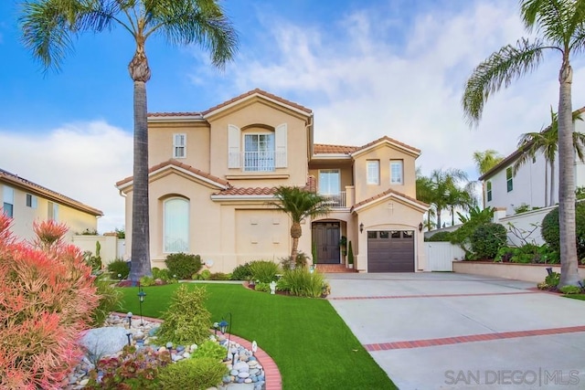 mediterranean / spanish home with a garage, a front lawn, and a balcony