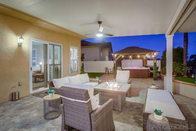 view of patio / terrace featuring ceiling fan, a hot tub, and an outdoor living space with a fire pit