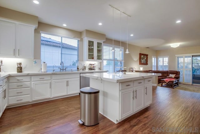 kitchen featuring a kitchen island, decorative light fixtures, white cabinetry, sink, and dark wood-type flooring