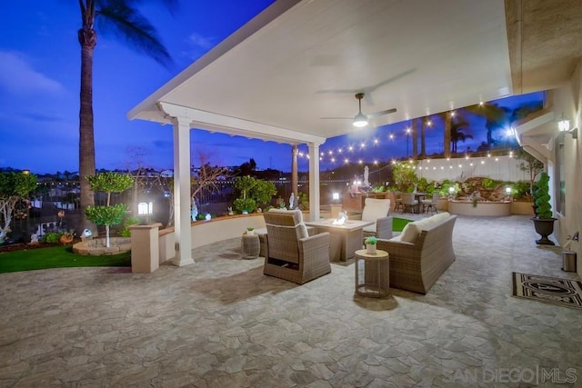 patio terrace at dusk featuring an outdoor living space with a fire pit and ceiling fan