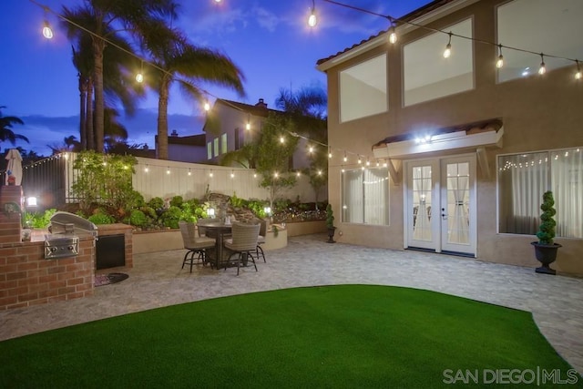 patio terrace at dusk with french doors and an outdoor kitchen