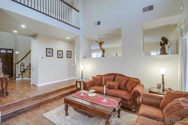 living room with a towering ceiling and light wood-type flooring