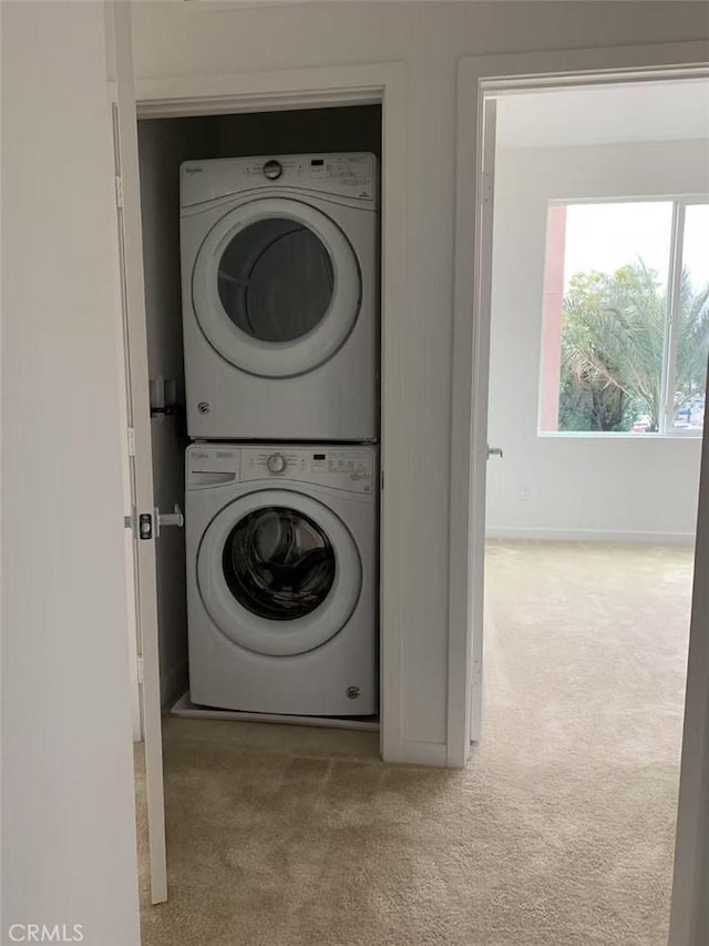 laundry room featuring stacked washer / drying machine and light carpet