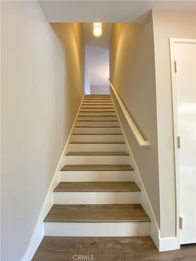 stairs featuring wood finished floors and baseboards