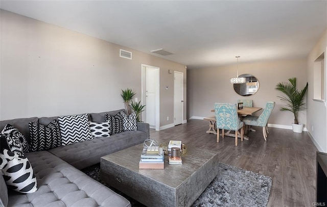 living room featuring visible vents, baseboards, and wood finished floors