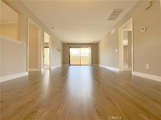 unfurnished living room with visible vents, baseboards, and wood finished floors