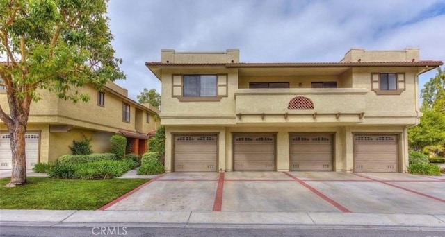 view of front of property featuring driveway, a balcony, an attached garage, and stucco siding