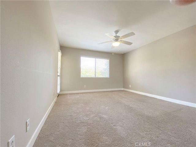 unfurnished room featuring a ceiling fan, light colored carpet, and baseboards