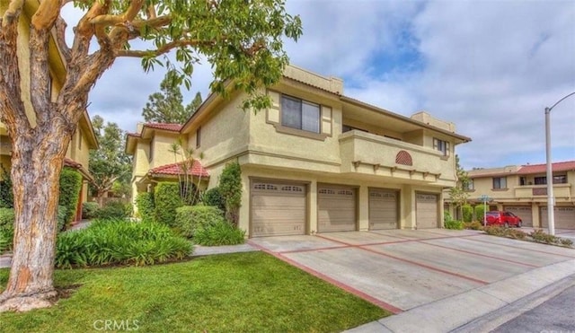 townhome / multi-family property with a garage, concrete driveway, and stucco siding