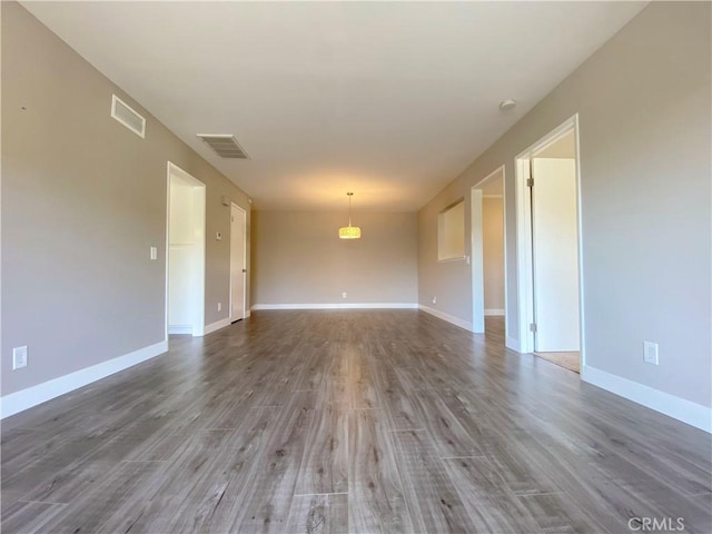 unfurnished room featuring visible vents, baseboards, and wood finished floors