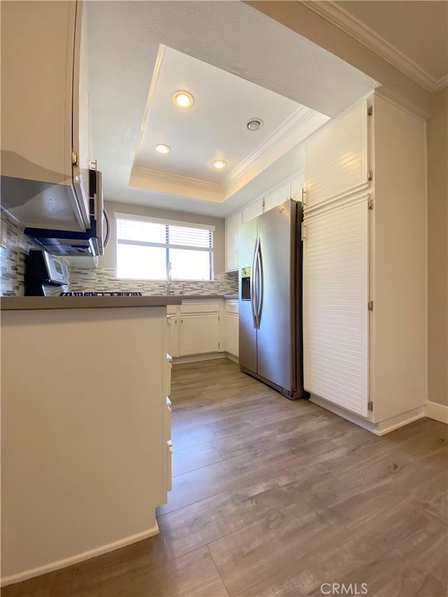 kitchen featuring light wood-type flooring, a tray ceiling, stainless steel refrigerator with ice dispenser, and crown molding