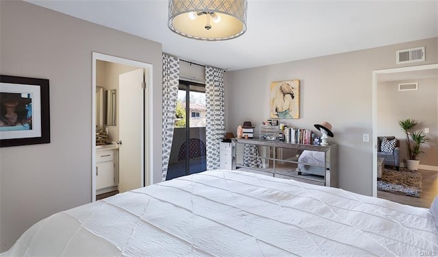 bedroom with baseboards, ensuite bath, visible vents, and wood finished floors