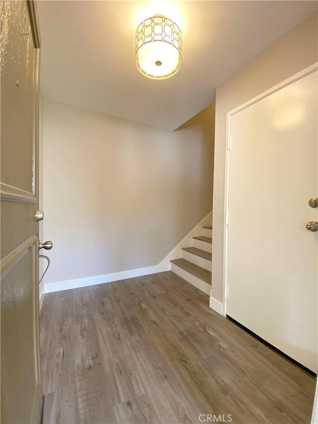 spare room with stairs, baseboards, and wood finished floors