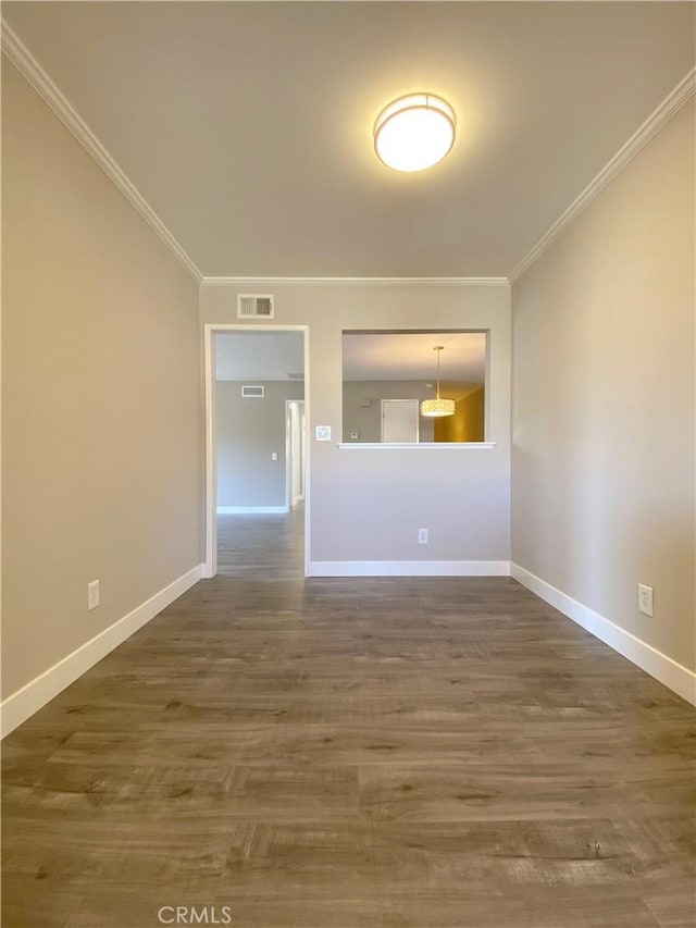 spare room with visible vents, crown molding, baseboards, and wood finished floors