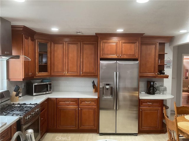 kitchen with wall chimney range hood, backsplash, and stainless steel appliances