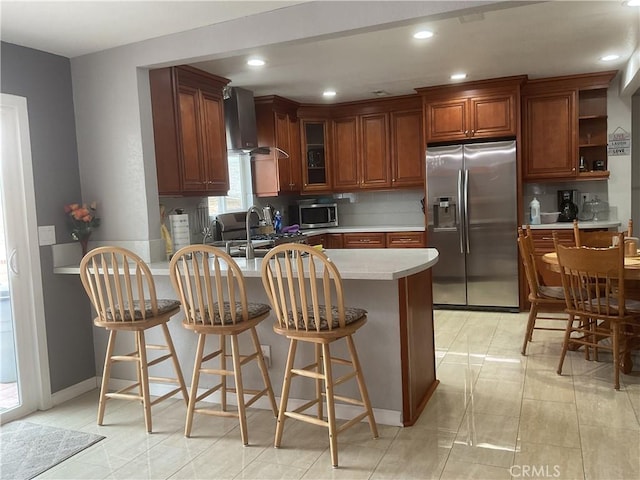 kitchen with sink, stainless steel appliances, decorative backsplash, kitchen peninsula, and wall chimney exhaust hood