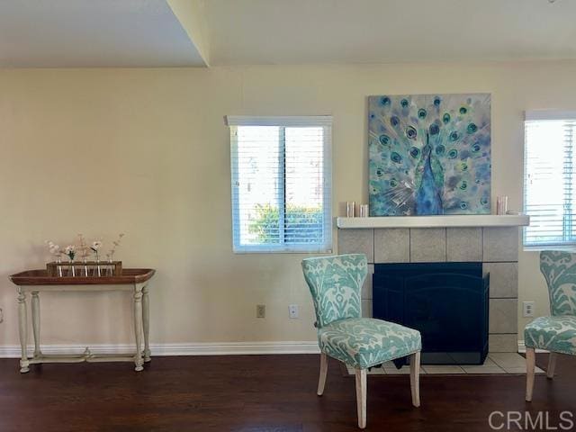 living area featuring a tile fireplace, wood finished floors, and baseboards