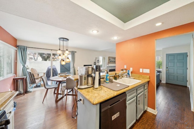 kitchen featuring dishwasher, dark wood-style floors, hanging light fixtures, light countertops, and a sink