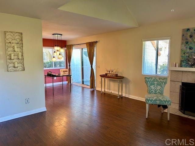 sitting room featuring a tile fireplace, an inviting chandelier, baseboards, and wood finished floors