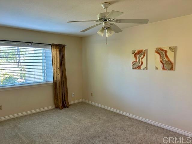 empty room with ceiling fan, carpet flooring, and baseboards